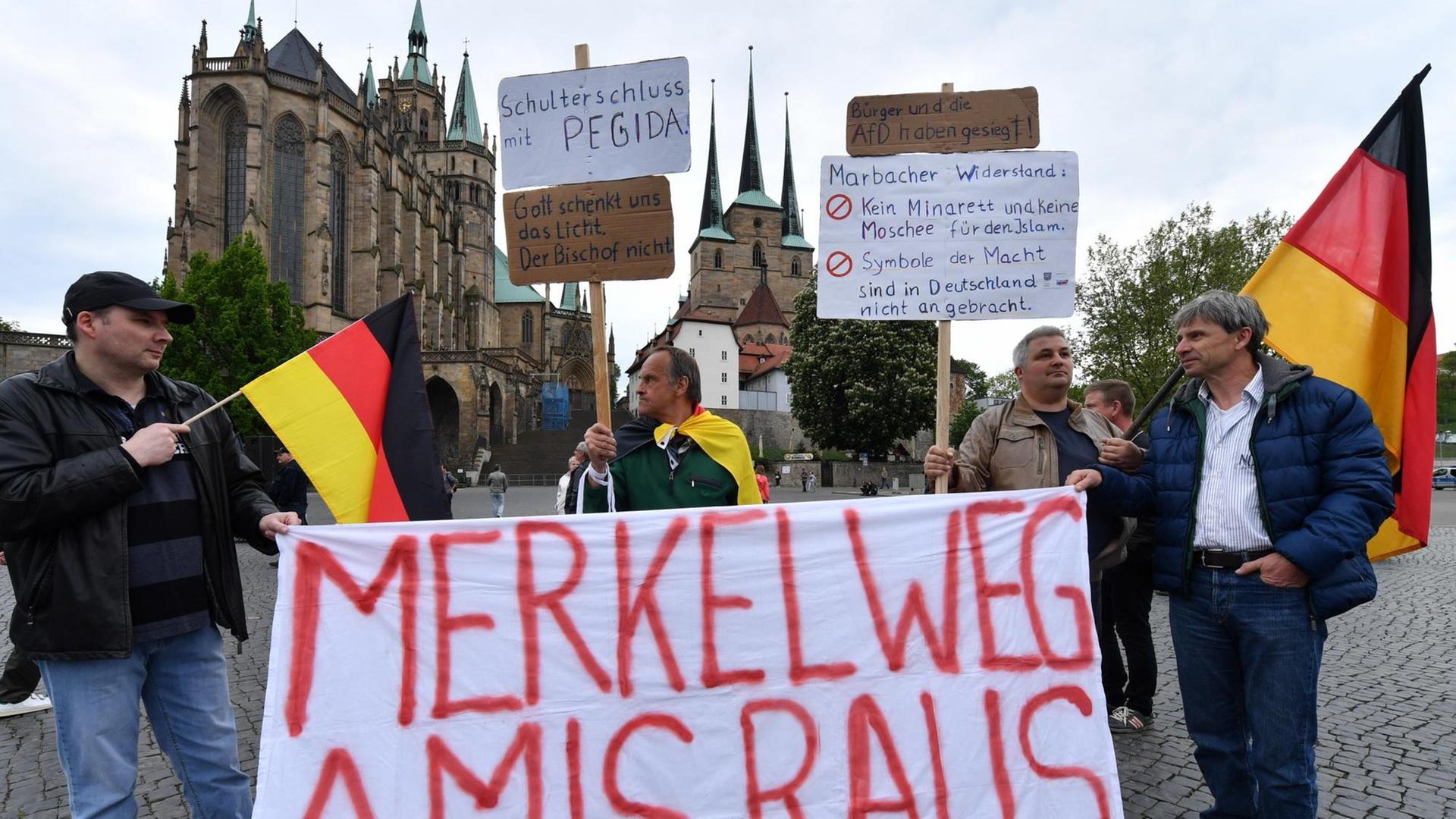 Demonstranten stehen auf dem Domplatz in Erfurt (Thüringen) bei einer Kundgebung der Alternative für Deutschland (AfD) gegen die Asyl- und Integrationspolitik von Bundes- und Landesregierung mit einem Banner mit der Aufschrift: "Merkel weg Amis raus".