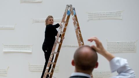 Zwei Mitarbeiter des Kunstmuseums bringen am 23.04.2014 in Wolfsburg (Niedersachsen) in der Ausstellung des Malers Oskar Kokoschka Zitate an einer weißen Wand an.