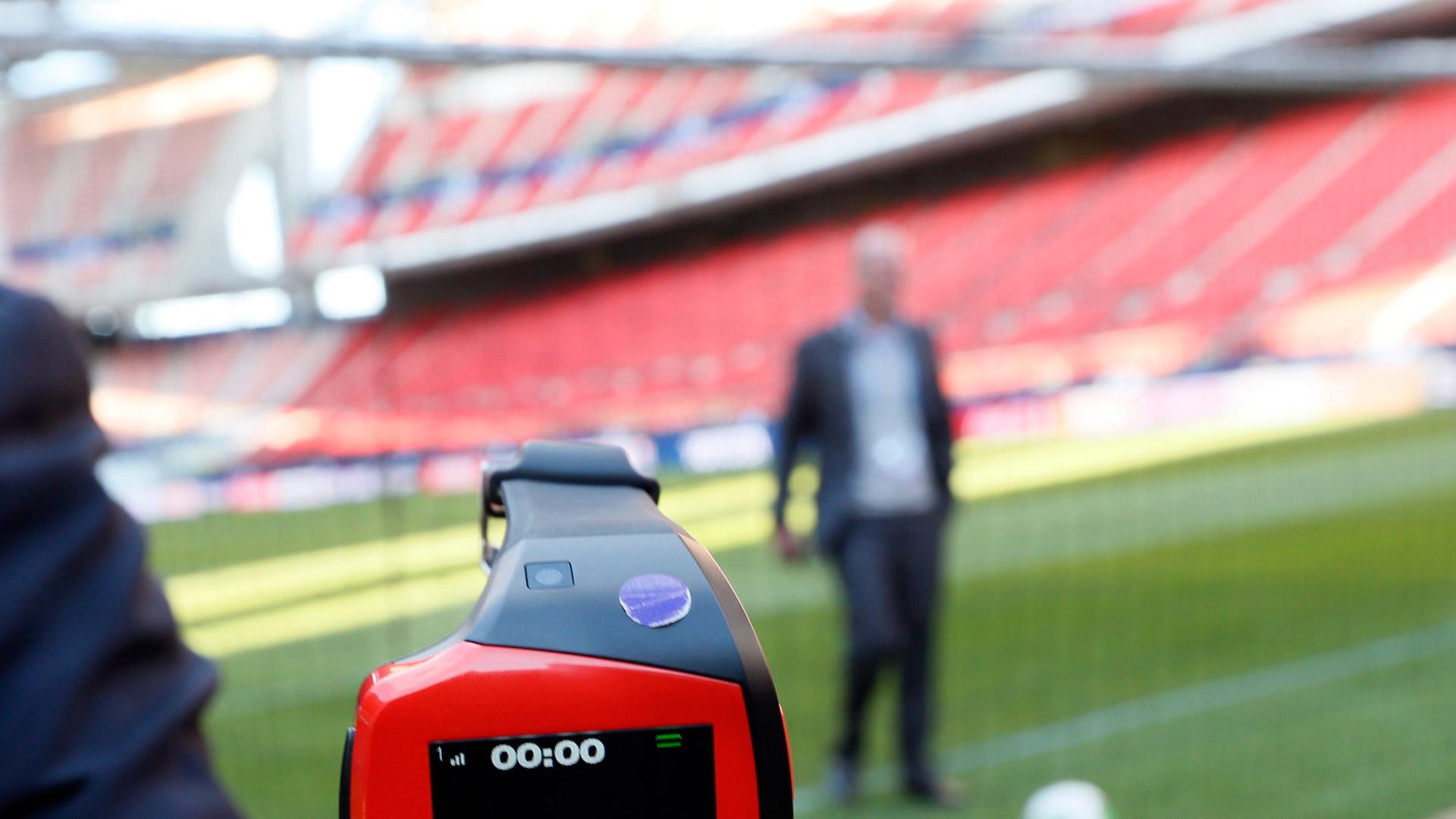Eine Art Armbanduhr mit der Aufschrift "Goal", im Hintergrund ein Ball in einem Tor in einem Fußballstadion. Eine Art Armbanduhr mit der Aufschrift "Goal", im Hintergrund ein Ball in einem Tor in einem Fußballstadion.