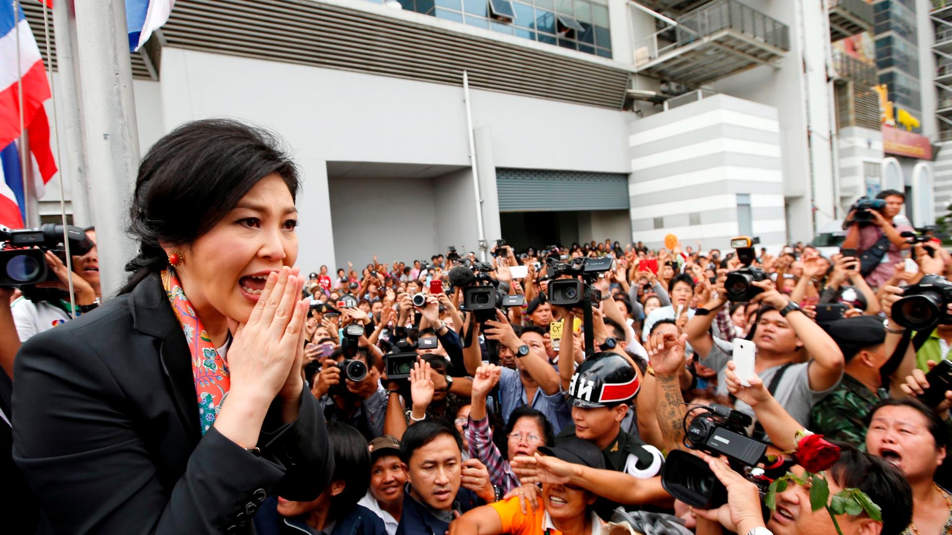 epa04194659 Thai caretaker Prime Minister Yingluck Shinawatra (L) greets supporters in traditional Thai way after she was removed from office at the Office of the Permanent Secretary for Defense in Bangkok, Thailand, 07 May 2014. Thai caretaker Prime Mini