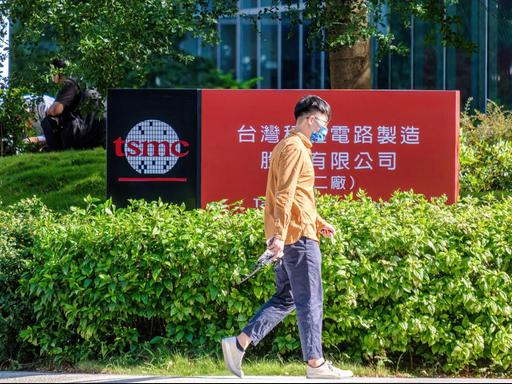 Eine Person mit Coronamaske läuft vor einem Firmengebäude von TSMC (Taiwan Semiconductor Manufacturing Company) in Hsinchu, Taiwan, entlang.