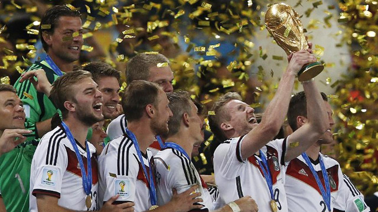 Die Nationalspieler stehen in einem Regen aus goldenen Papierschnipseln und halten den WM-Pokal in die Luft.