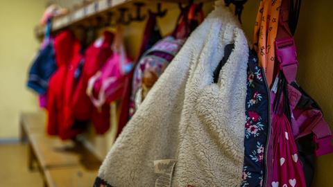 An einer Garderobe in einem Kindergarten hängen Jacken und Rucksäcke von Kindern.