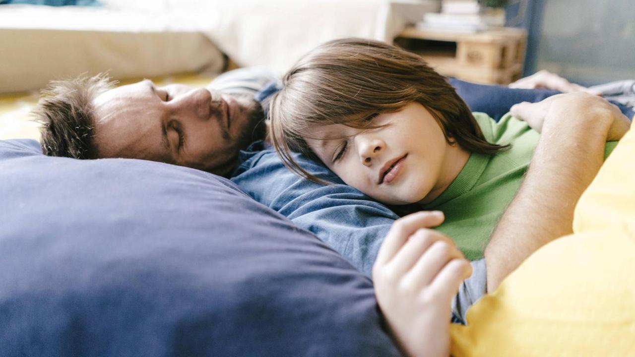 Vater und Sohn schlafend, in liebevoller Umarmung.