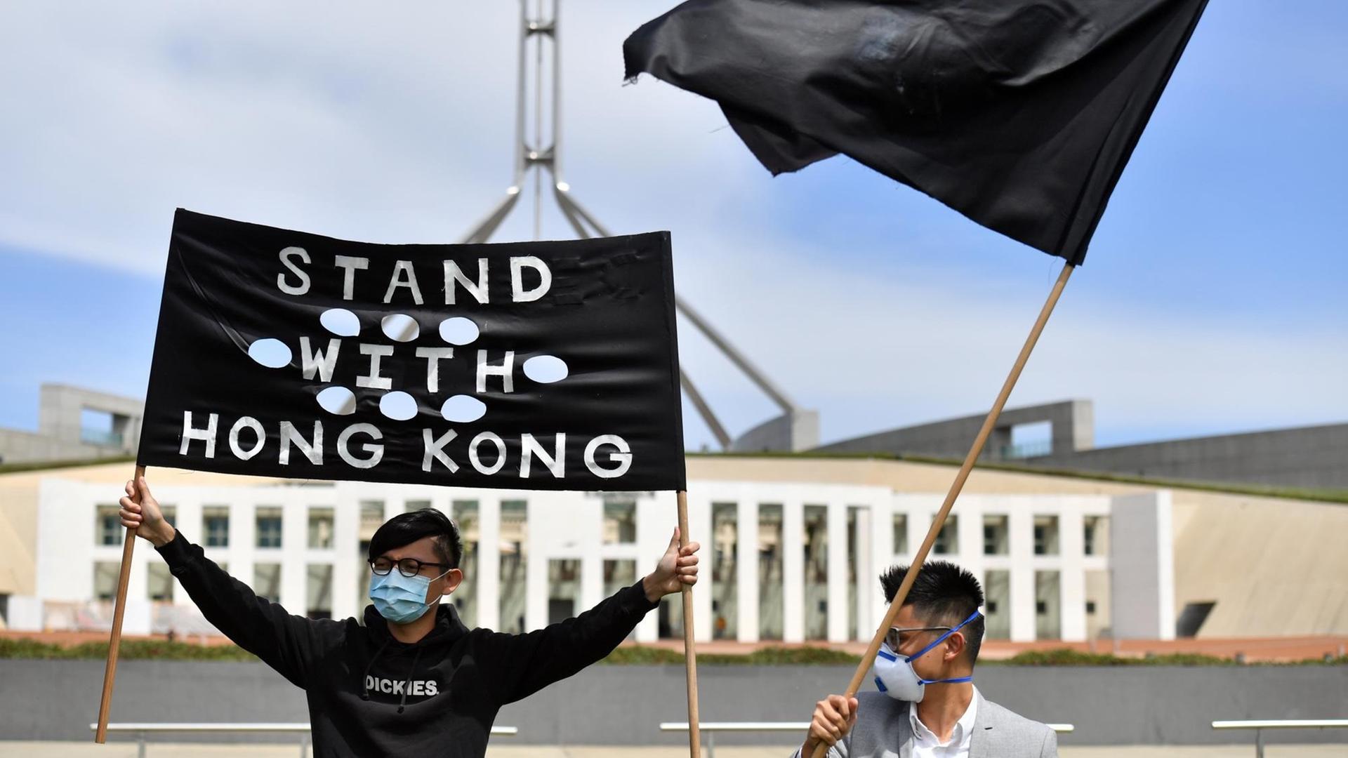 Junge Männer demonstrieren mit schwarzen Flaggen für Demokratie in Hongkong.