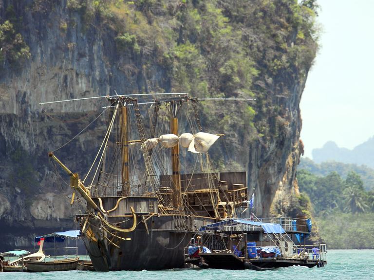Ein historisches Segelschiff vor Inselpanorama.