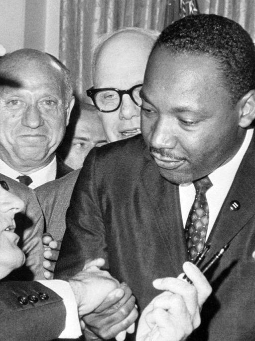 Nach der Unterzeichnung des Bürgerrechts-Gesetzes am 2.7.1964 in Washington DC. reicht US-Präsident Lyndon Baines Johnson (l) den Federhalter an den Bürgerrechtler Martin Luther King weiter und gibt ihm die Hand. Das Bürgerrechtsgesetz sollte eine Gleichberechtigung der farbigen Bevölkerung in den Vereinigten Staaten von Amerika garantieren und galt als eine der wichtigsten Gesetzes-Entscheidungen in der Geschichte der USA. King wurde am 4.4.1968 im Alter von 39 Jahren in Memphis von James Earl Ray erschossen.