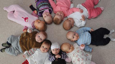 Babys liegen Kopf an Kopf in einem Kreis auf dem Boden.