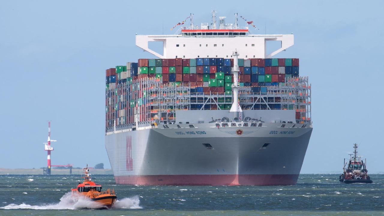 Der Containerschiff-Neubau MV "OOCL Hong Kong" läuft in den JadeWeserPort in Wilhelmshaven ein. Im Vordergrund kreuzt ein Lotsenboot den Weg des Containerriesen.