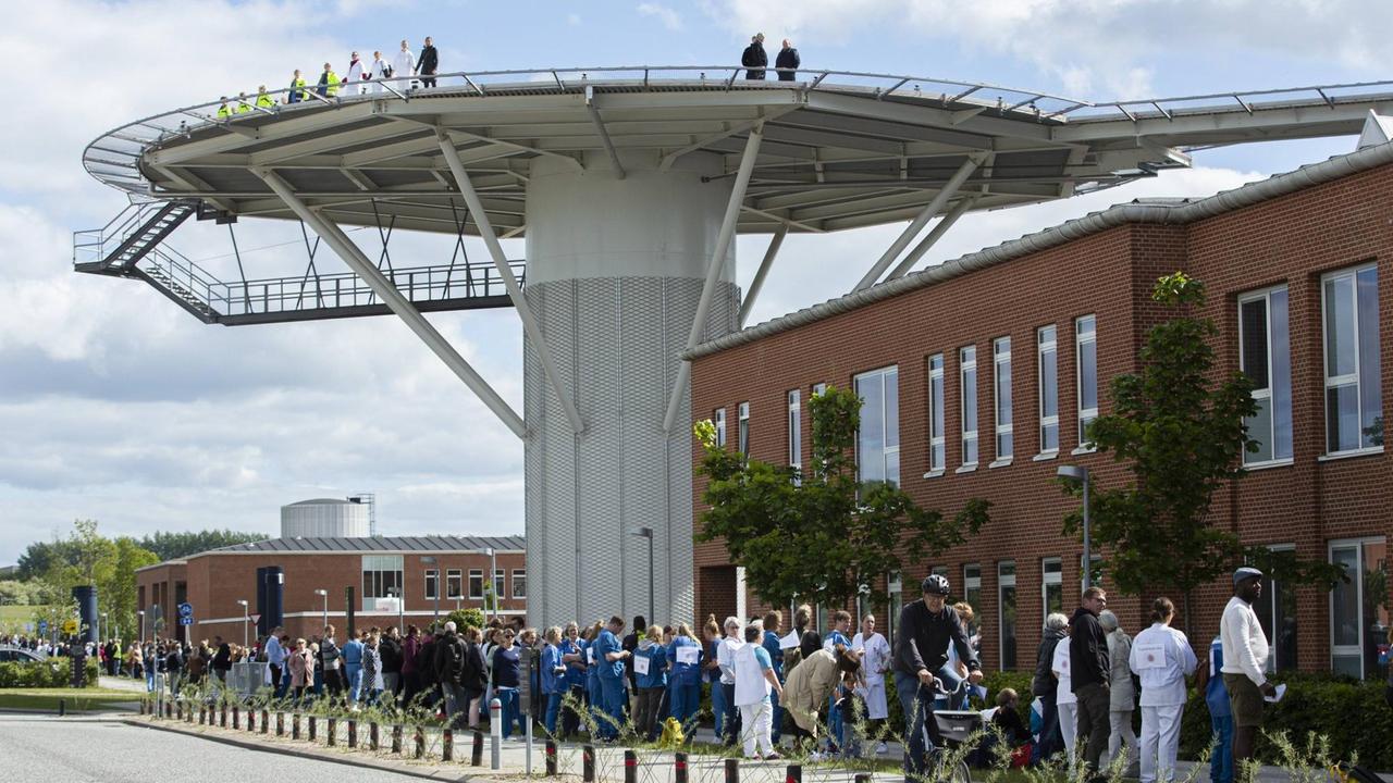 Angestellte des Aarhuser Universitätsklinikums formen eine Menschenkette um das Gebäude um gegen Kürzungen ihrer finanziellen Mittel zu protestieren.