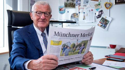 Zeitungsverleger, hält eine Tageszeitung in seinem Büro in seinen Händen.