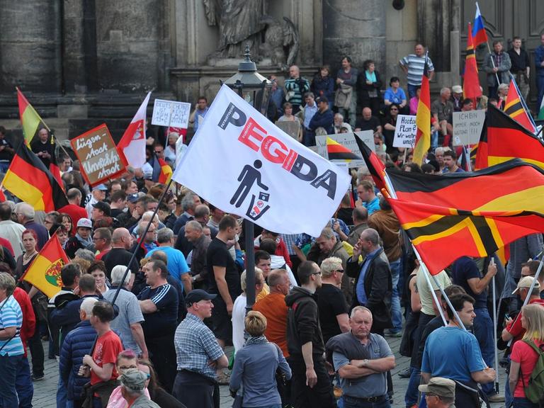 Einige hundert Anhänger des islamkritischen Bündnisses Pegida treffen sich am 04.05.2015 in Dresden (Sachsen) zu einer Kundgebung und halten Deutschland-Fahnen hoch.