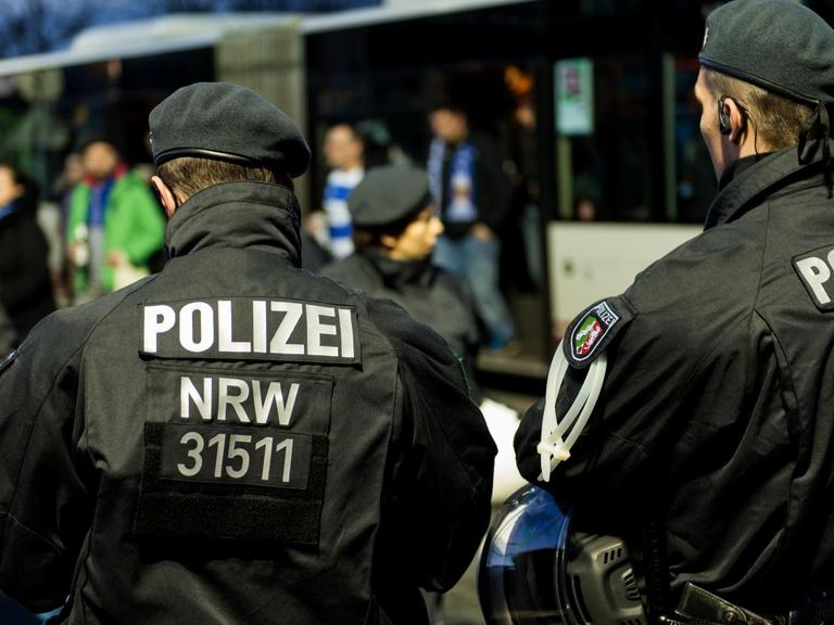 Zwei Polizeibeamten überwachen die Ankunft von Bussen mit Fußballfans vor dem Spiel zwischen Fortuna Düsseldorf und dem MSV Duisburg in der ESPRIT-Arena in Düsseldorf am 20.11.2015.