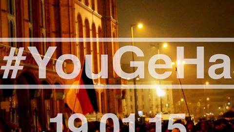 Screenshot des offiziellen #YouGeHa-Trailers. Schrift auf dem Foto von einer Pegida-Demonstration: Youtuber gegen Hass - #YouGeHa - am 19.01.15