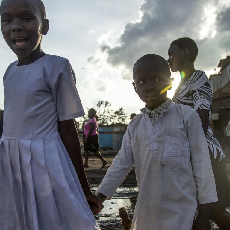 Kinder laufen über eine aufgeweichte Straße im Slum von Mathare in Nairobi /Kenia