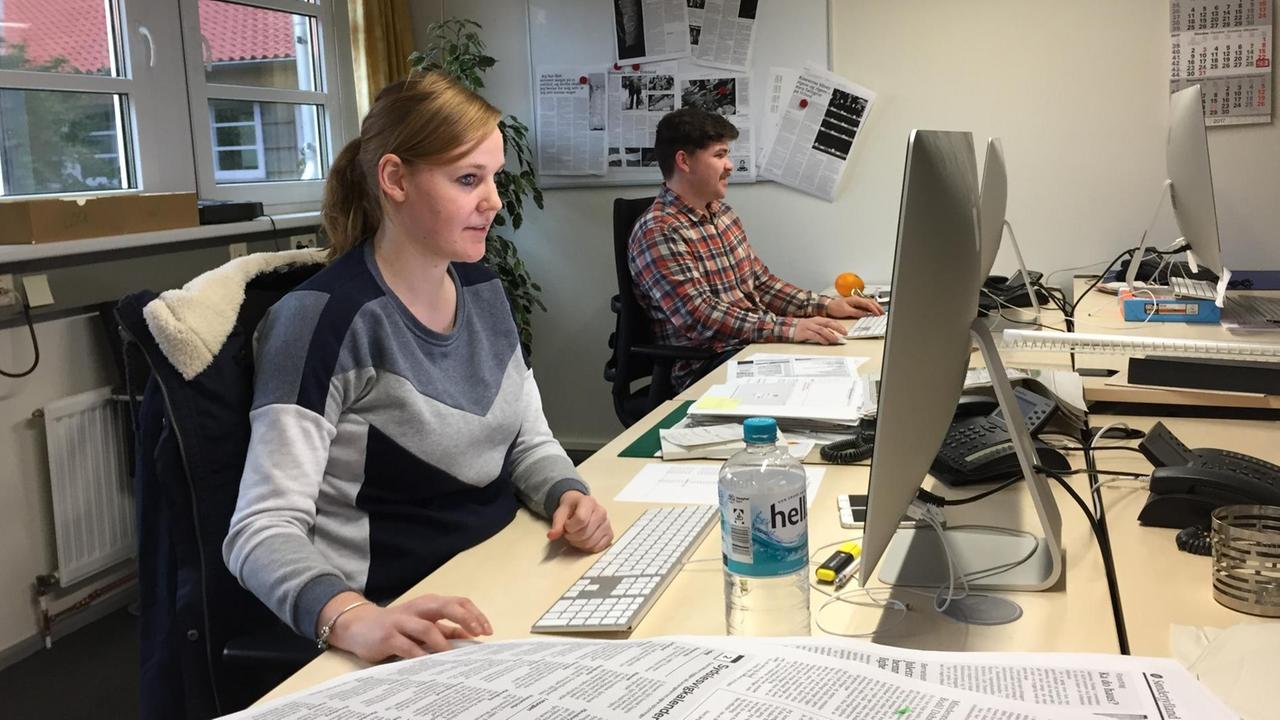 Journalistin May-Britt Petersen sitzt an einem Schreibtisch in der Redaktion der Tageszeitung Flensborg Avis.