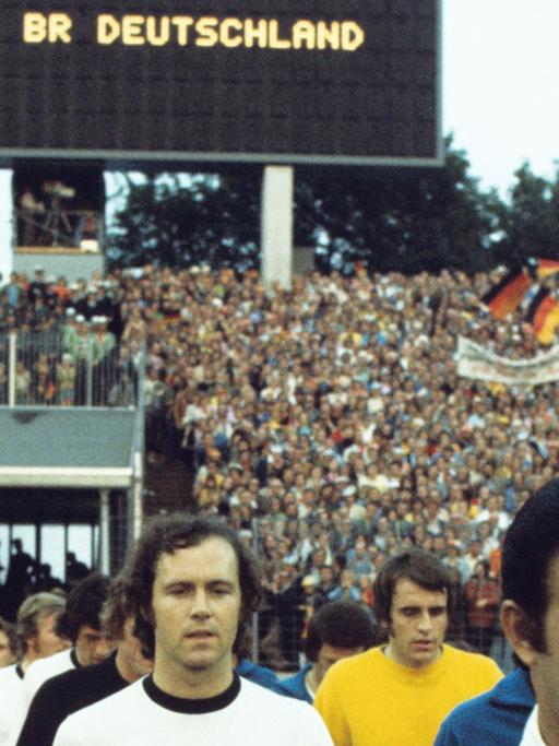 Der Kapitän der deutschen Fußball-Nationalmannschaft, Franz Beckenbauer, beim Einzug in des Volksparkstadion in Hamburg am 22.06.1974. Die bundesdeutsche Elf verlor in der Vorrunde der Fußball-Weltmeisterschaft das Spiel gegen die DDR überraschend mit 0:1 Toren. Torschütze war Jürgen Sparwasser. Ganz rechts der Schiedsrichter Ramon Bareto Ruiz (Uruguay).