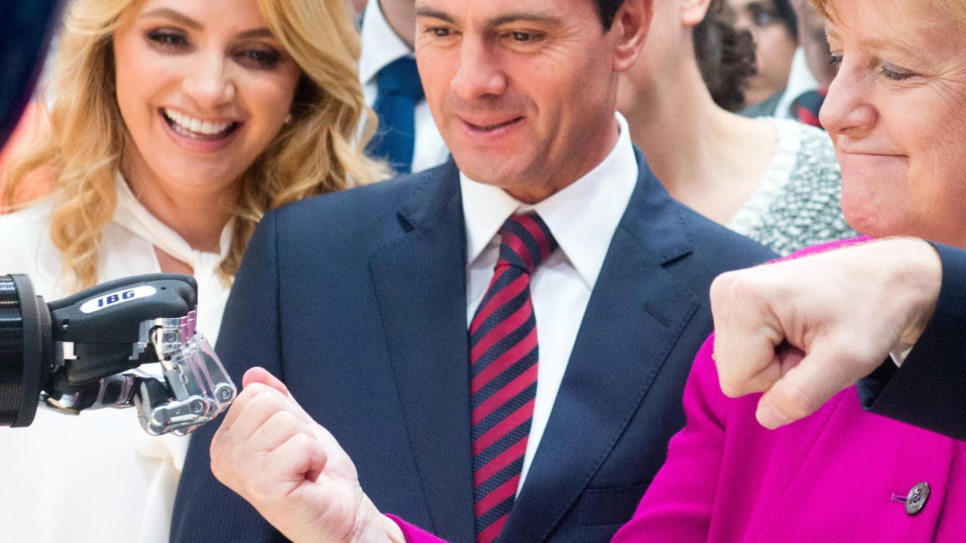 Bundeskanzlerin Angela Merkel (r, CDU) und Enrique Pena Nieto, Präsident des Gastlandes Mexiko, mit seiner Frau Rivera de Peno gehen bei der Hannover Messe 2018 am Stand von IGB Automation auf Tuchfühlung mit einer Roboterhand.