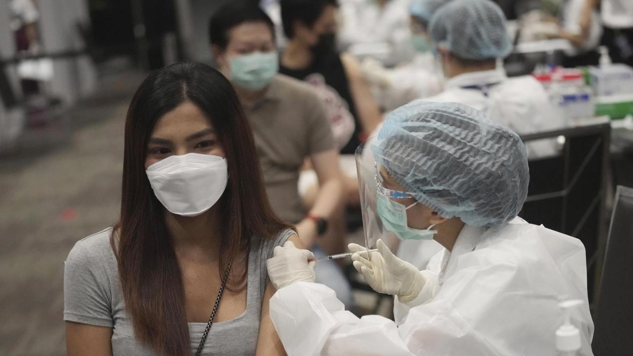 Eine junge Frau erhält in einem Einkaufszentrum in Bangkok eine Impfung gegen das Coronavirus.