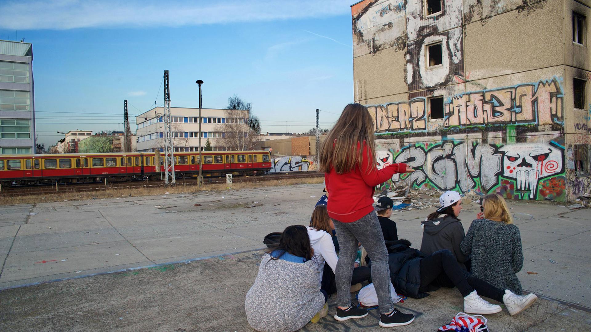 Jugendliche auf einer Brache vor einer Ruine (Plattenbau) in Berlin