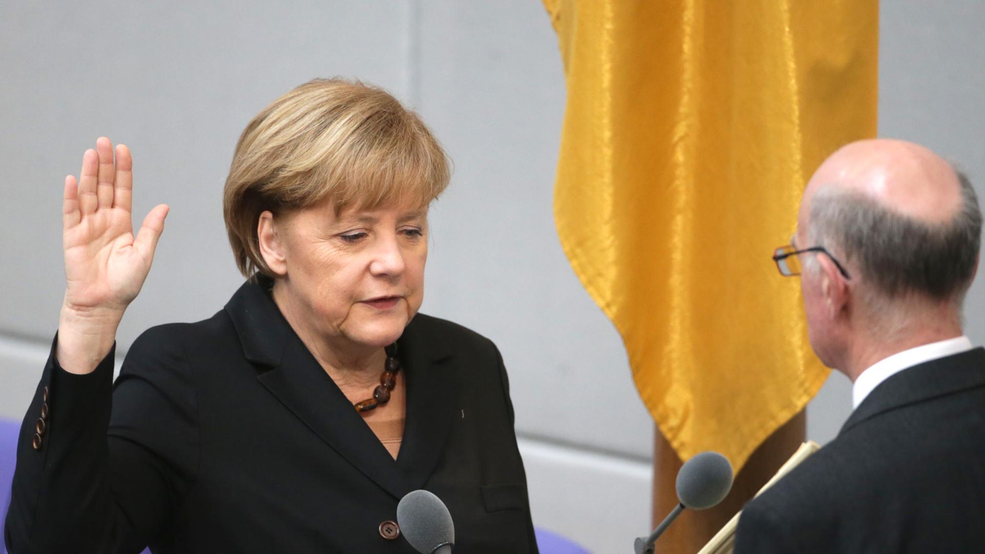 Bundeskanzlerin Angela Merkel steht im Bundestag in Berlin vor Parlamentspräsident Norbert Lammert und legt den Amtseid ab.