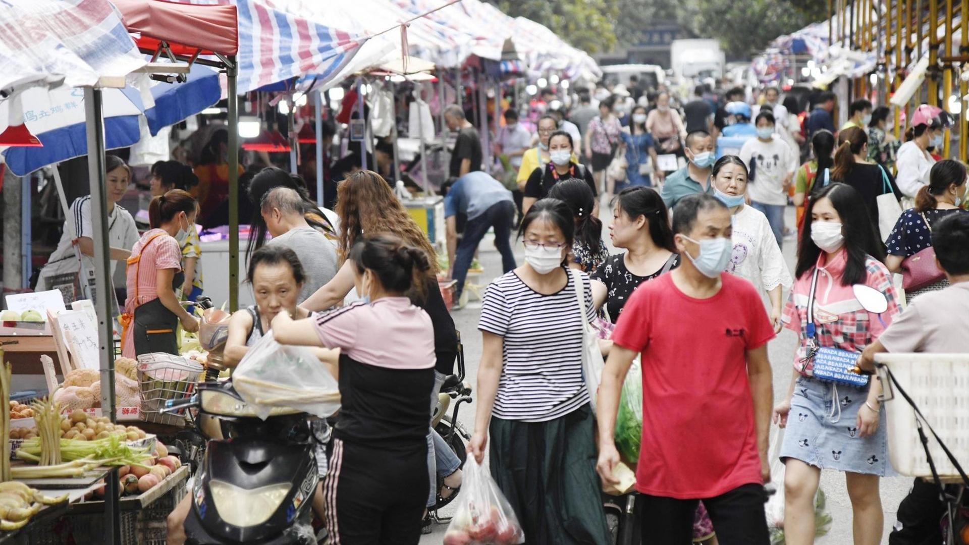 Leben in Wuhan - Menschen kaufen in der Innenstadt auf einem Markt ein