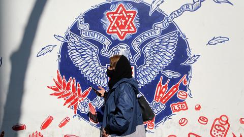 Eine Frau läuft in Teheran an einem Straßengraffiti vorbei.