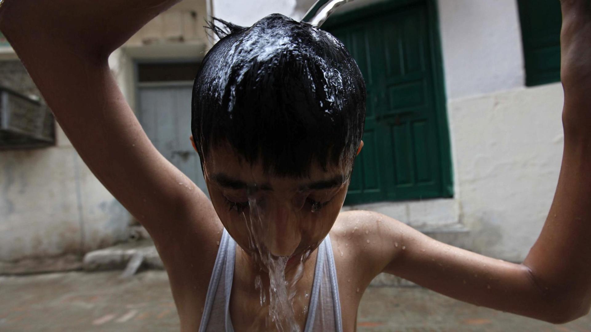 Ein Junge kühlt sich in Peshawar in Pakistan mit Wasser.