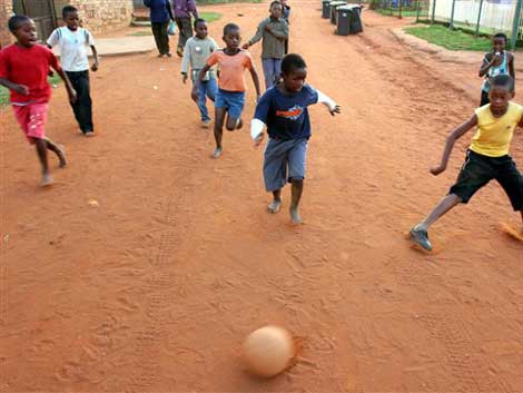 Kinder spielen in Soweto auf der Straße Fußball.