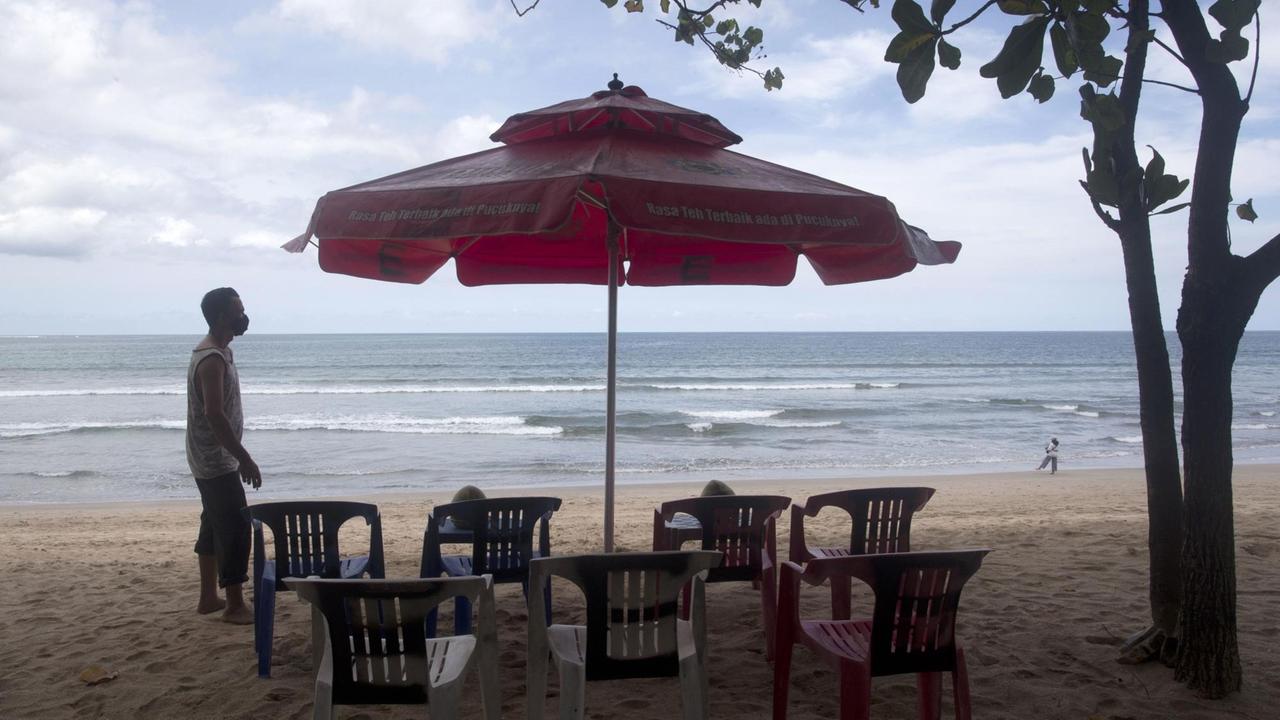 Ein Tisch, Stühle und ein Sonnenschirm am Strand von Bali.