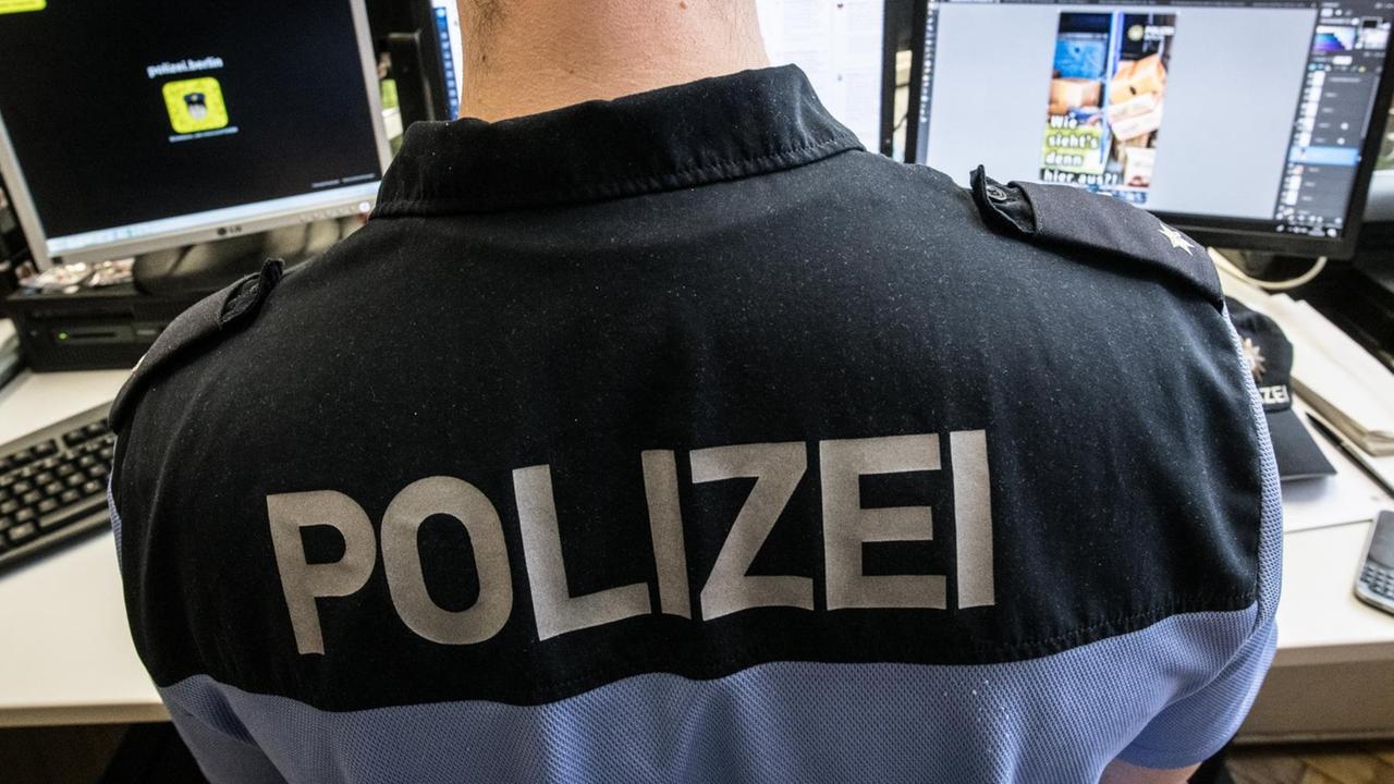 Ein Polizist sitzt in einem Raum vor seinen Computern.