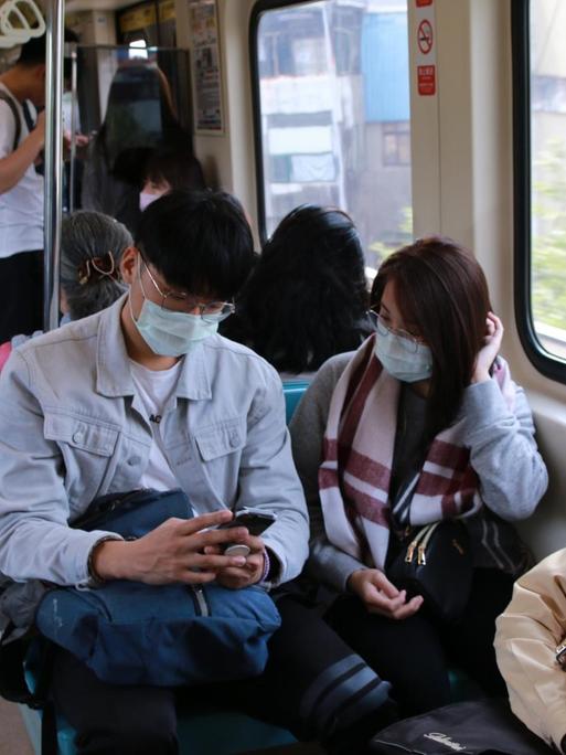 Menschen tragen Mundschutz in der Metro von Taipeh