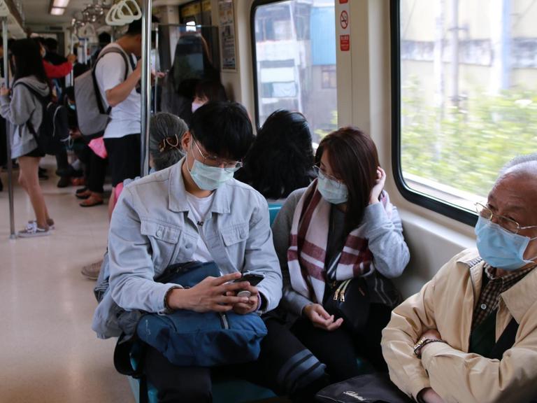 Menschen tragen Mundschutz in der Metro von Taipeh