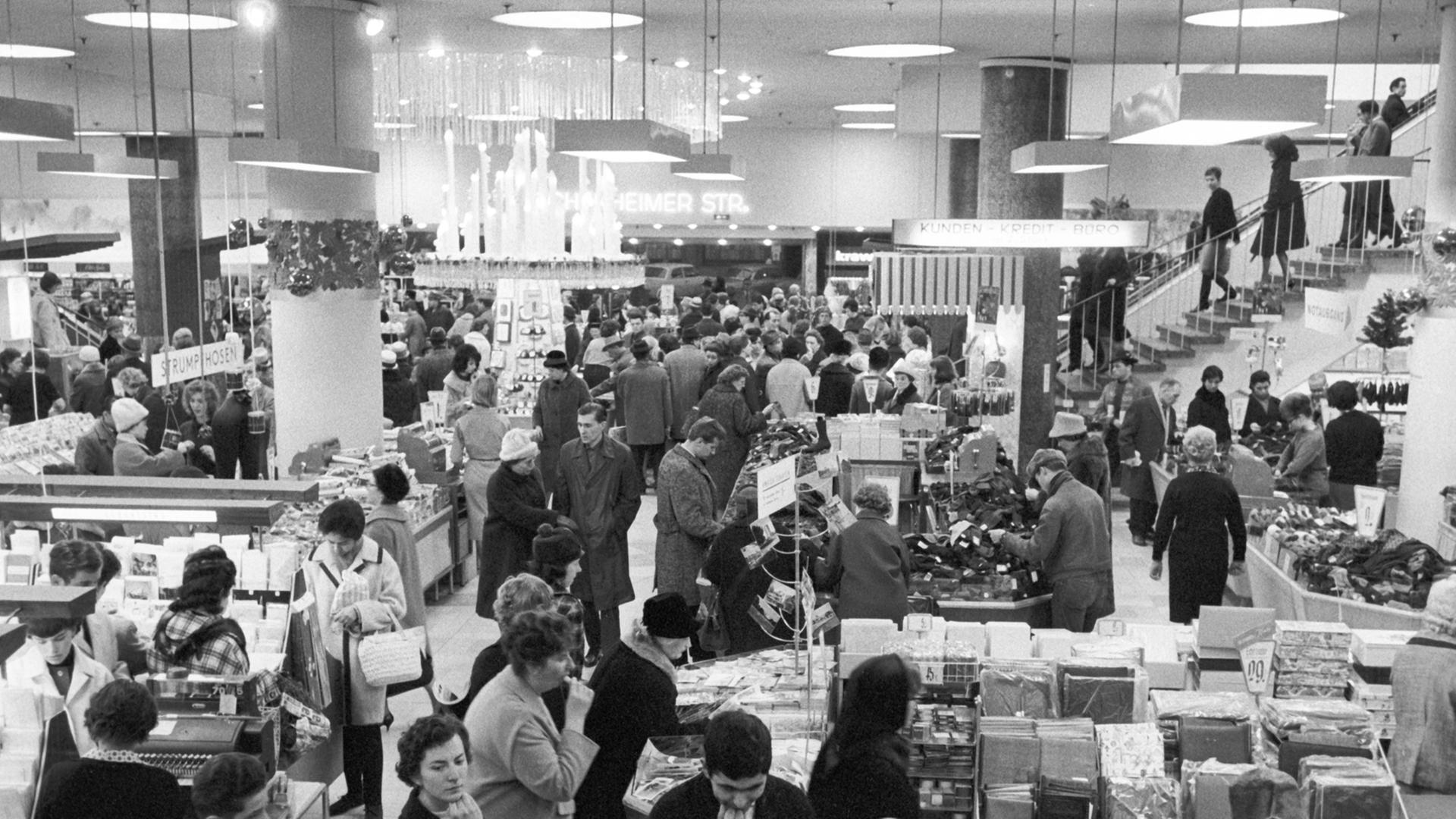 Blick in ein Frankfurter Kaufhaus am 3.12.1963, Schwarz-Weiß-Aufnahme, Menschen stehen an Kassen und Verkaufsständen