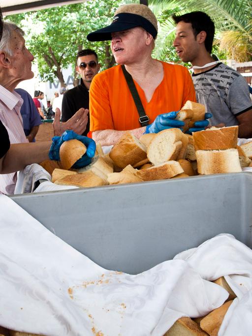 Zu sehen ist eine Essensausgabe in Athen. Einheimische und Migranten erhalten von freiwilligen Helfern Lebensmittel.