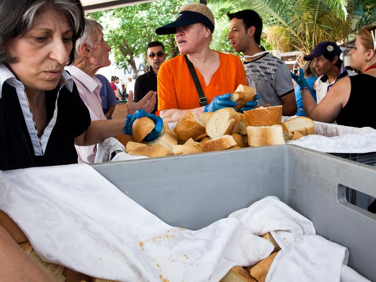 Zu sehen ist eine Essensausgabe in Athen. Einheimische und Migranten erhalten von freiwilligen Helfern Lebensmittel.