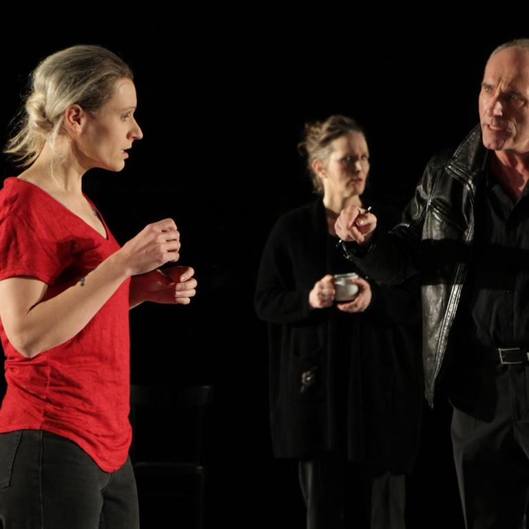 Nadine Geyersbach, Irene Kleinschmidt und Martin Baum (v.l.) in "Aus dem Nichts" am Theater Bremen in der Regie von Nurkan Erpulat. Ein Schauspieler und zwei Schauspielerinnen stehen auf einer Theaterbühne. Der Mann und eine der Frauen führen ein Gespräch.