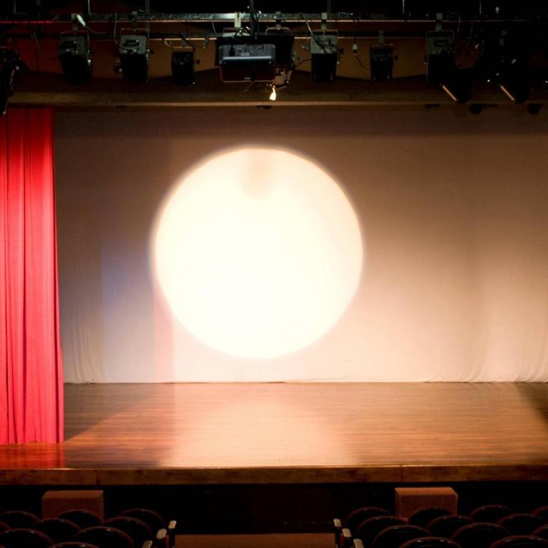 Leere Theaterbühne mit rotem Vorhang.