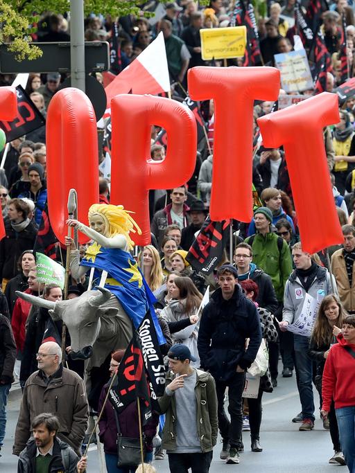 Demonstranten tragen am 23.04.2016 Fahnen und Banner während einer Demonstration gegen das umstrittene transatlantische Freihandelsabkommen TTIP in Hannover.