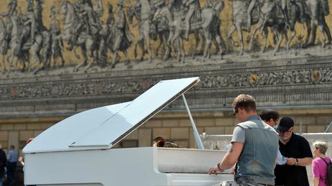 Ein Pianist spielt in Dresden vor dem Fürstenzug