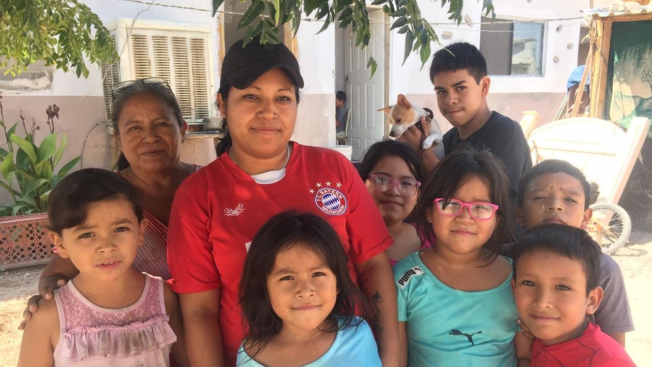 Gruppenbild der Arbeiterin Cinthia Mora im roten T-Shirt mit dem Logo des FC Bayern München und ihren Kindern.