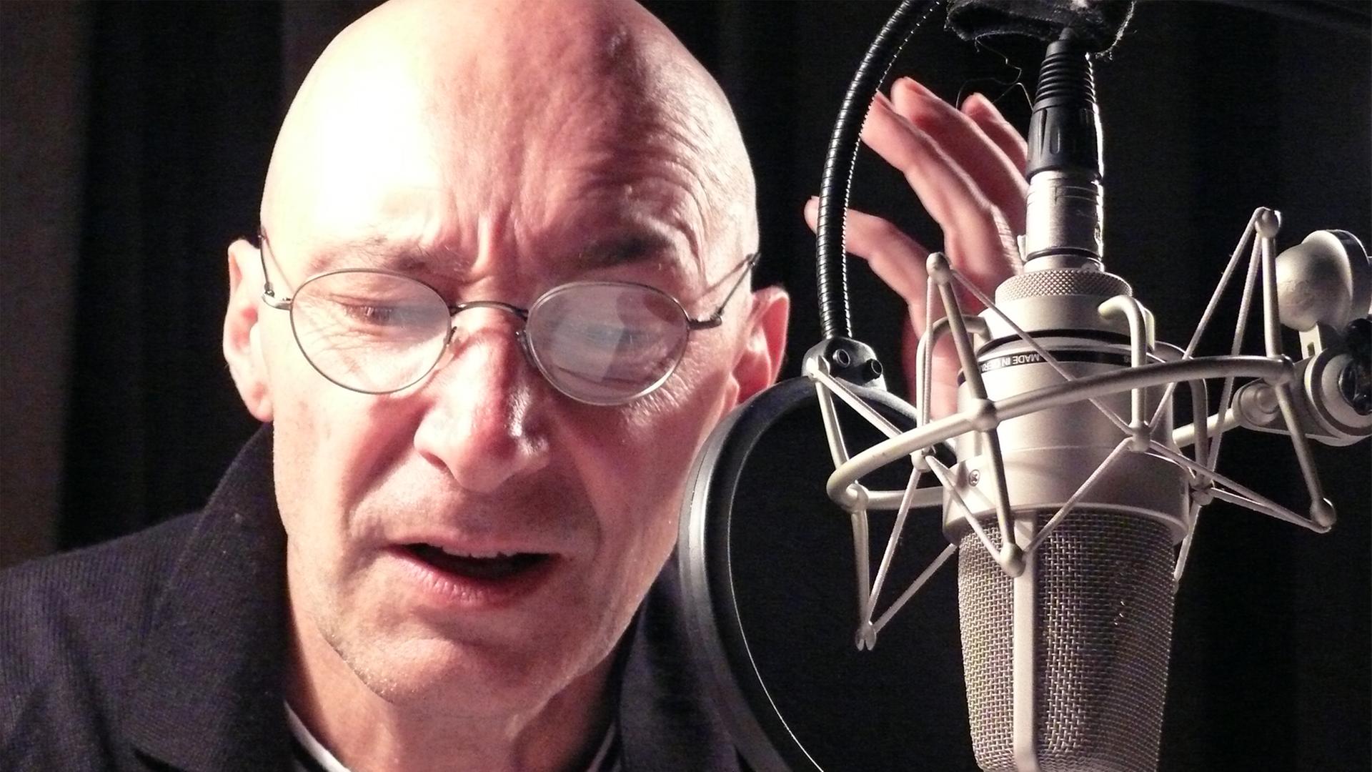 Der Schauspieler Andreas Grothgar während einer Hörspielaufnahme im Studio am Mikrofon.