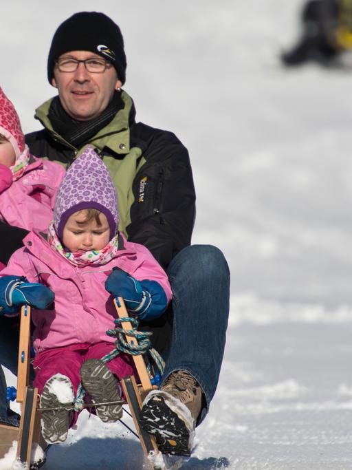 Ein Vater fährt auf dem Schauinsland bei Hofsgrund (Baden-Württemberg) mit den Zwilllingen Sophia und Ann auf dem Schlitten durch den Schnee.