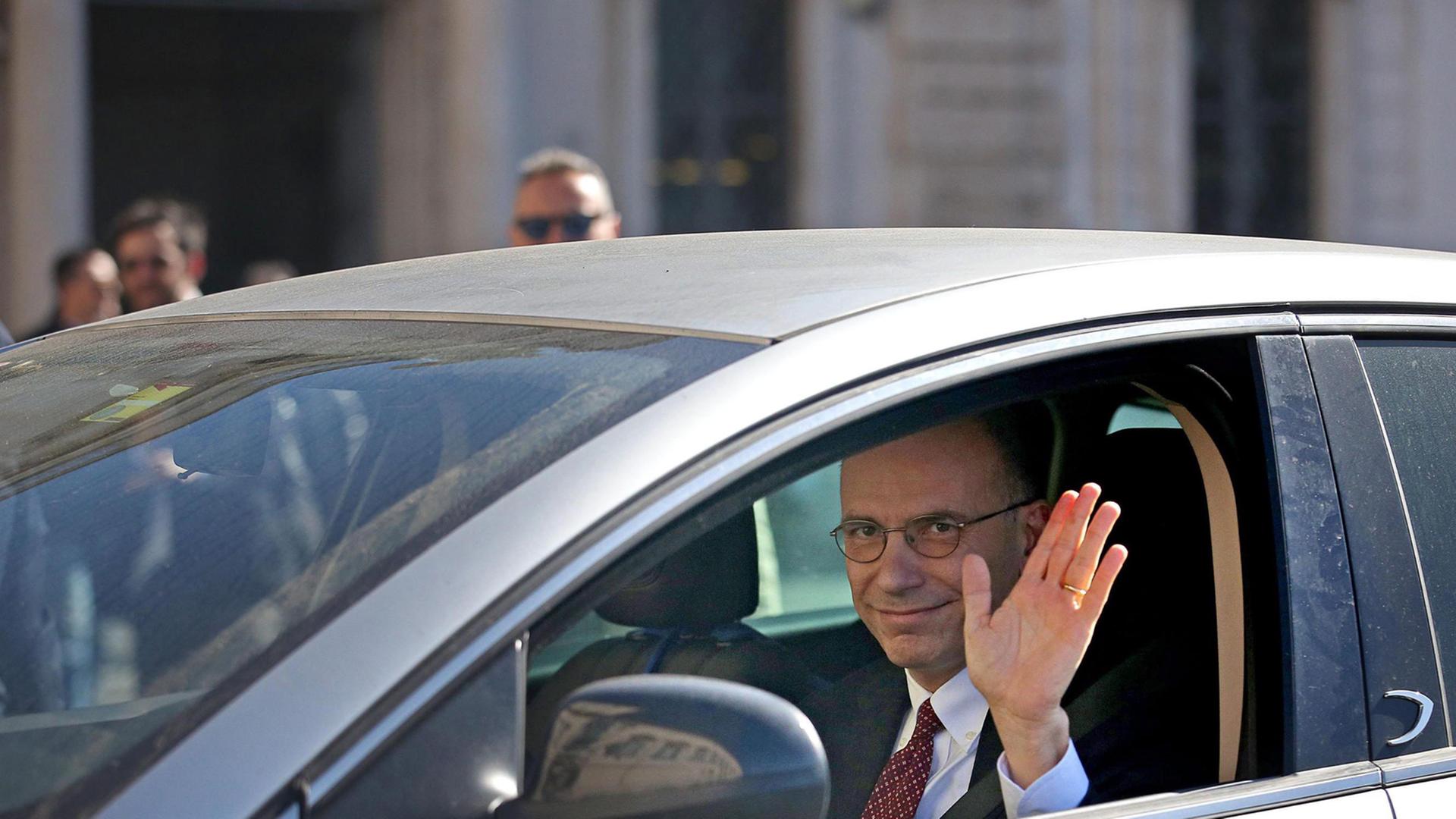 Italiens Ex-Ministerpräsident Enrico Letta winkt aus einem Auto den Journalisten zu