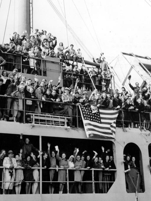 Sogenannte Displaced Persons auf dem US-Transporter "Marine Flasher" winken beim Auslaufen des Schiffs am 10. Mai 1946 in Bremerhaven zum Abschied. Sie konnten im Rahmen des US-Einwanderungsprogramms in die Vereinigten Staaten auswandern.