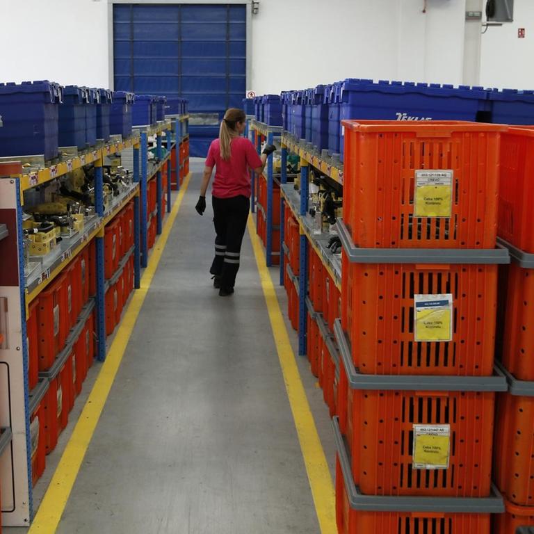 Eine Frau läuft durch einen Gang, der von Regalen gesäumt ist in einem türkischen Unternehmen in Serbien