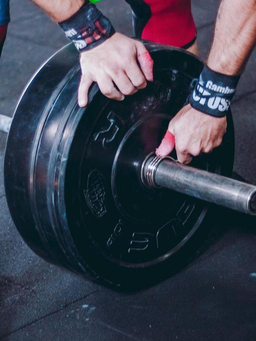 Ein Sportler sichert die Gewichte an der Hantel.