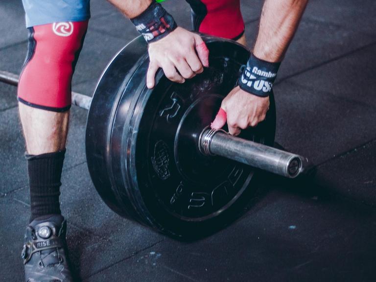 Ein Sportler sichert die Gewichte an der Hantel.