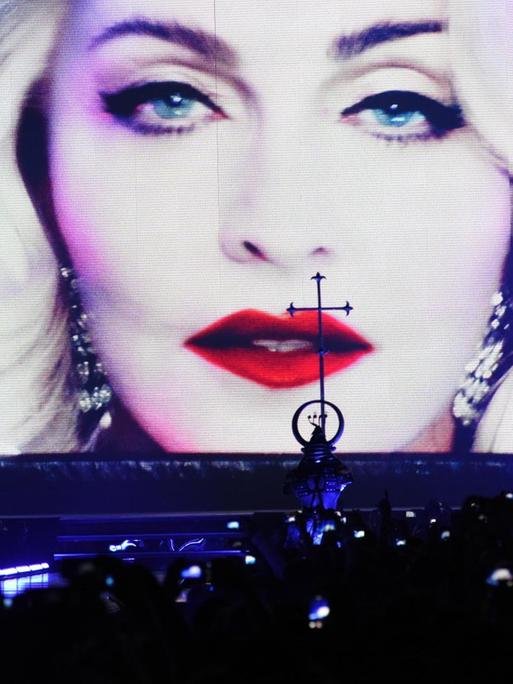 Das Gesicht Madonnas in Nahaufnahme auf einen großen Leinwand vor Konzertpublikum