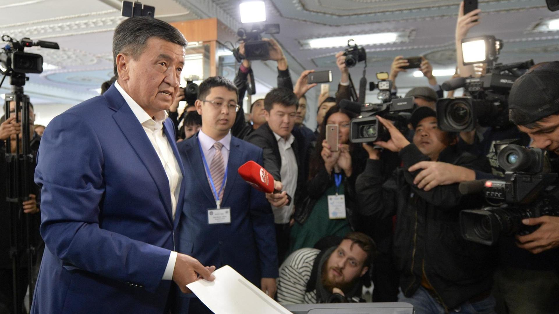 Der kirgisische Präsidentschaftskandidat Soroonbaj Scheenbekow (l) gibt am 15.10.2017 in einem Wahllokal in Bischkek (Kirgistan) seinen Stimmzettel ab.